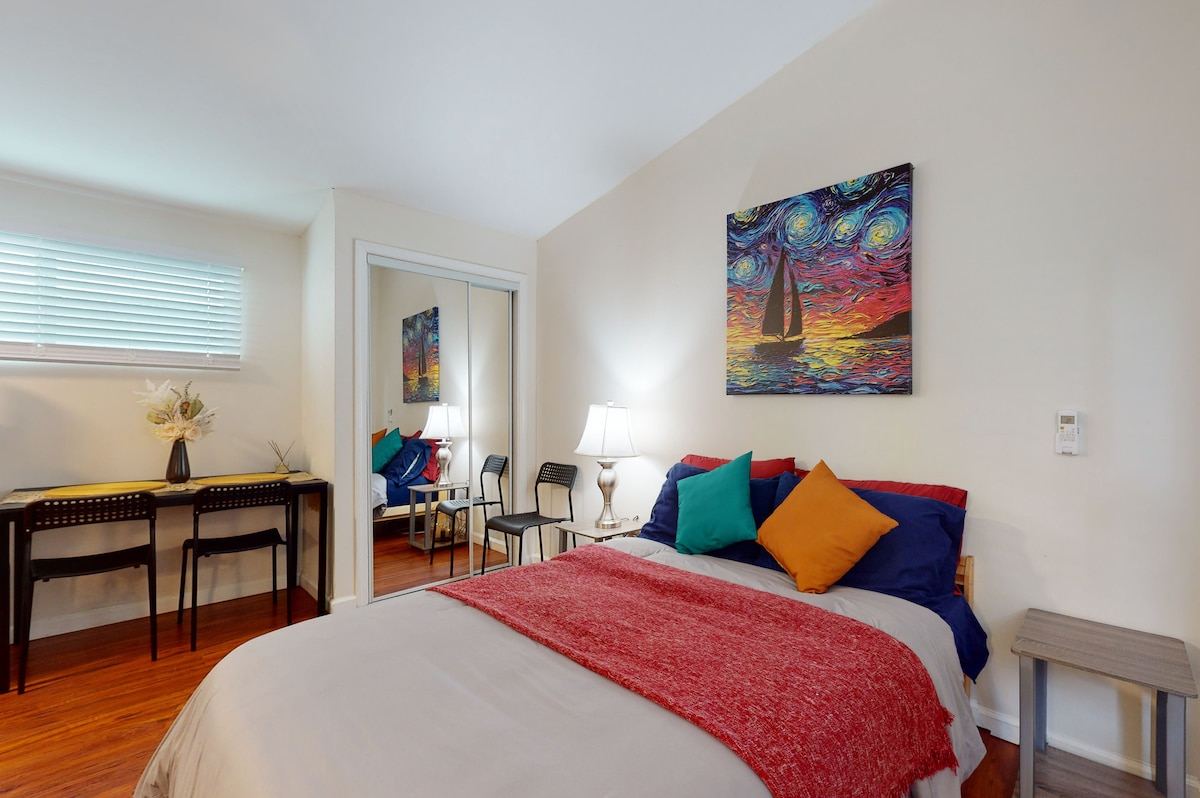 Queen bedroom with mirrored closet, work desk, and colorful sailboat artwork — Hawthorne