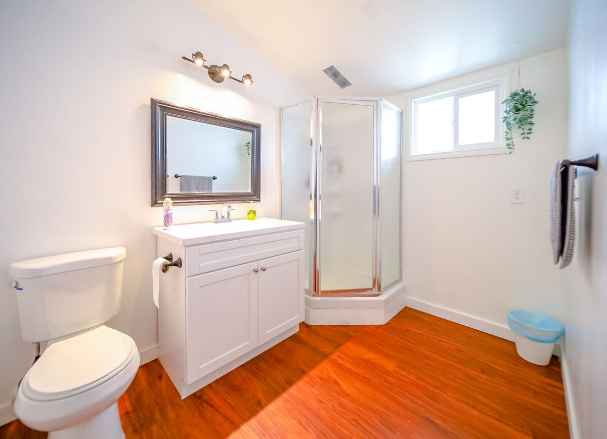 Bathroom with corner shower stall, white vanity, and framed mirror — Hawthorne