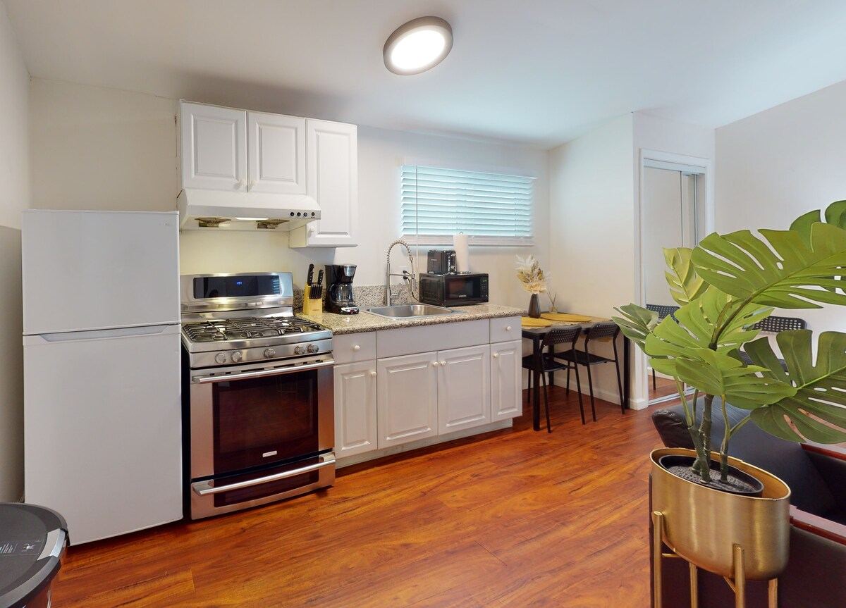 Kitchenette with gas range, white cabinetry, and breakfast-bar seating — Hawthorne
