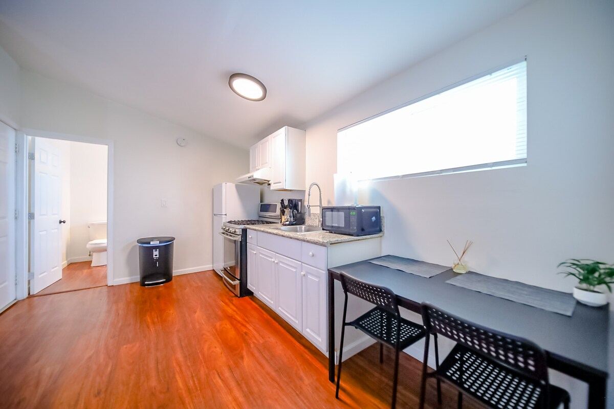 Compact kitchen and dining area with hardwood floors and bathroom doorway — Hawthorne